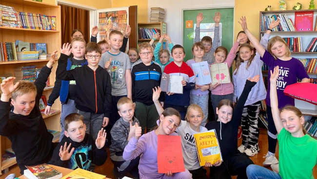 Grupa uczniów w bibliotece szkolnej.