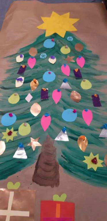 Praca Świetliczaków - choinka namalowana na szarym papierze z różnokolorowymi ozdobami wykonanymi z papieru.