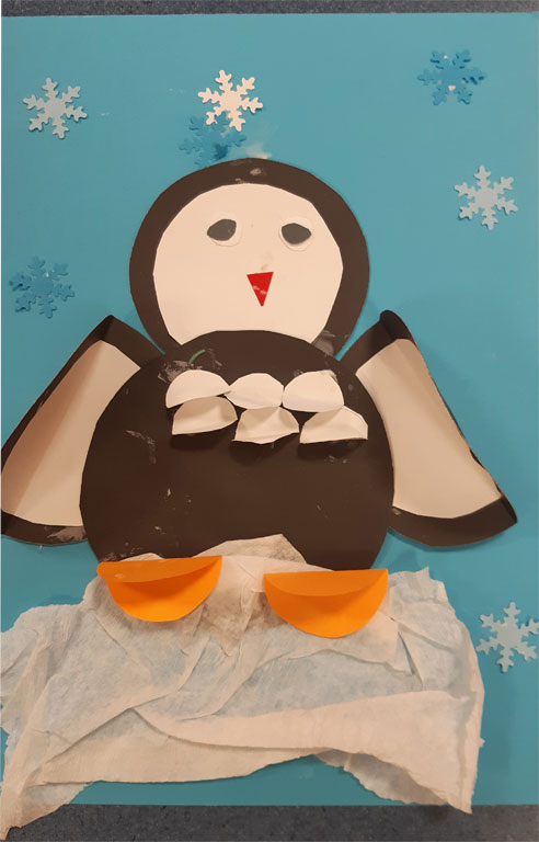 Praca Świetliczaka - Na niebieskim tle pingwin wykonany z papieru.