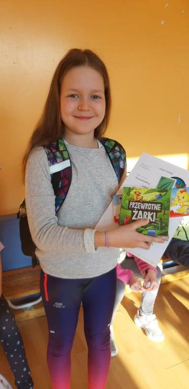 Pomarańczowe tło, dziewczynka, która trzyma ksiązki i dyplom.