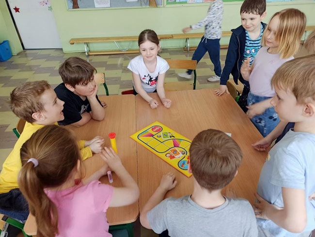 Świetlica szkolna - grupa dzieci, na stole gra planszowa.